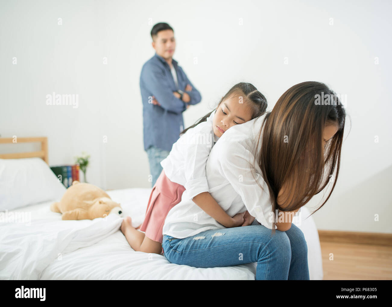 A little girl sad with her parents are arguing in the background bed room, Asian happy loving family.Soft and select focus. Stock Photo