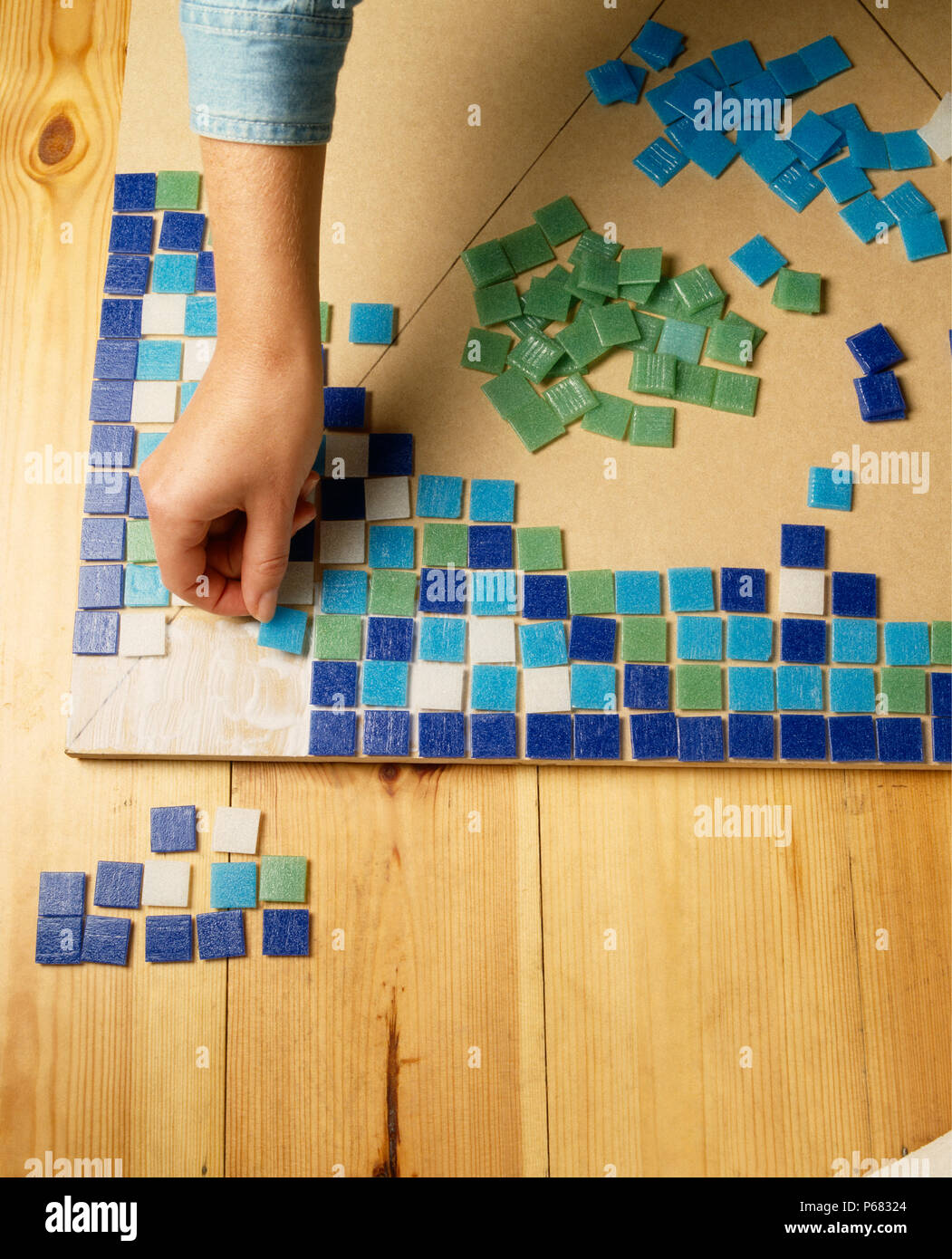 Close-up of hands arranging mosaic tiles for table top FOR EDITORIAL ...