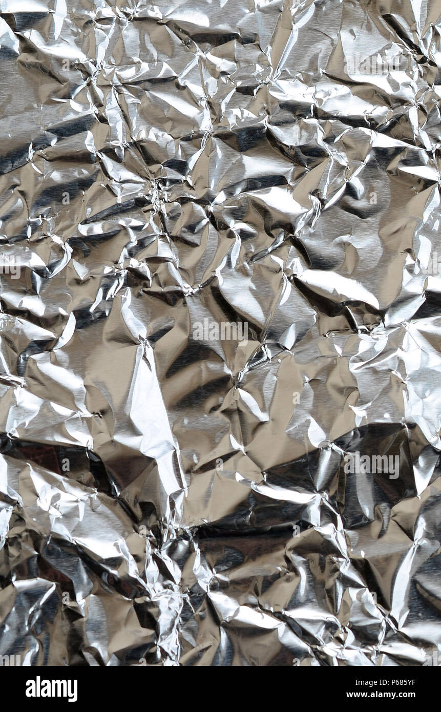 Thin wrinkled sheet of crushed tin aluminum silver foil background with