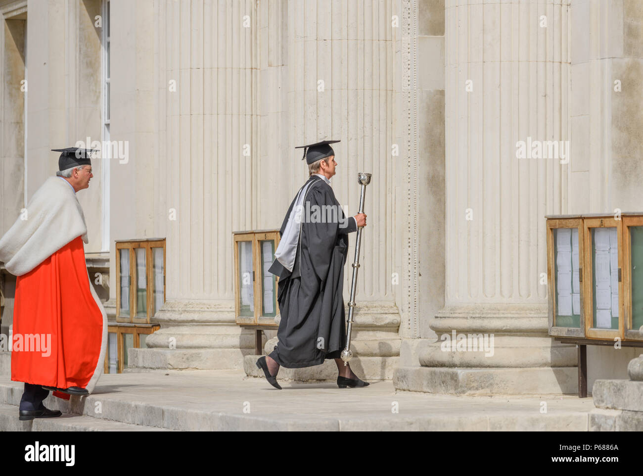 Cambridge, England. 28 June 2018. The vice-chancellor of Cambridge University, England, dressed in his crimson academic gown, and preceded as well as followed by esquire bedells with maces, processes through the grounds of Senate House to the main building where he presides at the degree/graduation ceremony on 28th June 2018. Credit: Michael Foley/Alamy Live News Stock Photo