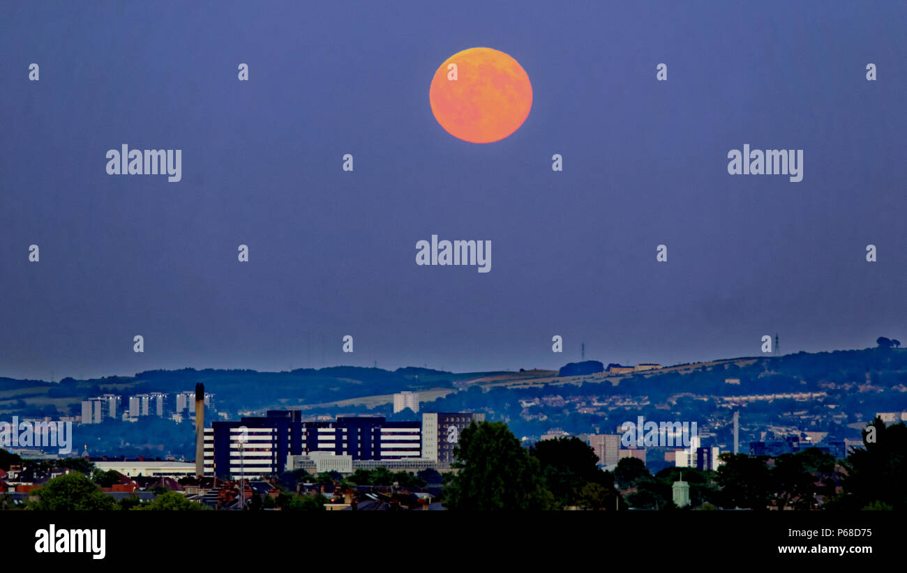 Glasgow, Scotland, UK 28th June. UK Weather:Sunny sizzling weather causes clear skies as a Strawberry full moon over the city appears over yorkhill hospital  Cathkin braes and Dechmont hill also known as hot or mead moon or rose moon. Credit: gerard ferry/Alamy Live News Stock Photo
