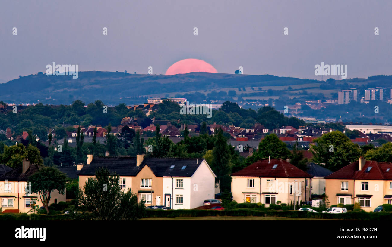 Glasgow, Scotland, UK 28th June. UK Weather:Sunny sizzling weather causes clear skies as a Strawberry full moon over the city appears over Cathkin braes and Dechmont hill also known as hot or mead moon or rose moon. Credit: gerard ferry/Alamy Live News Stock Photo