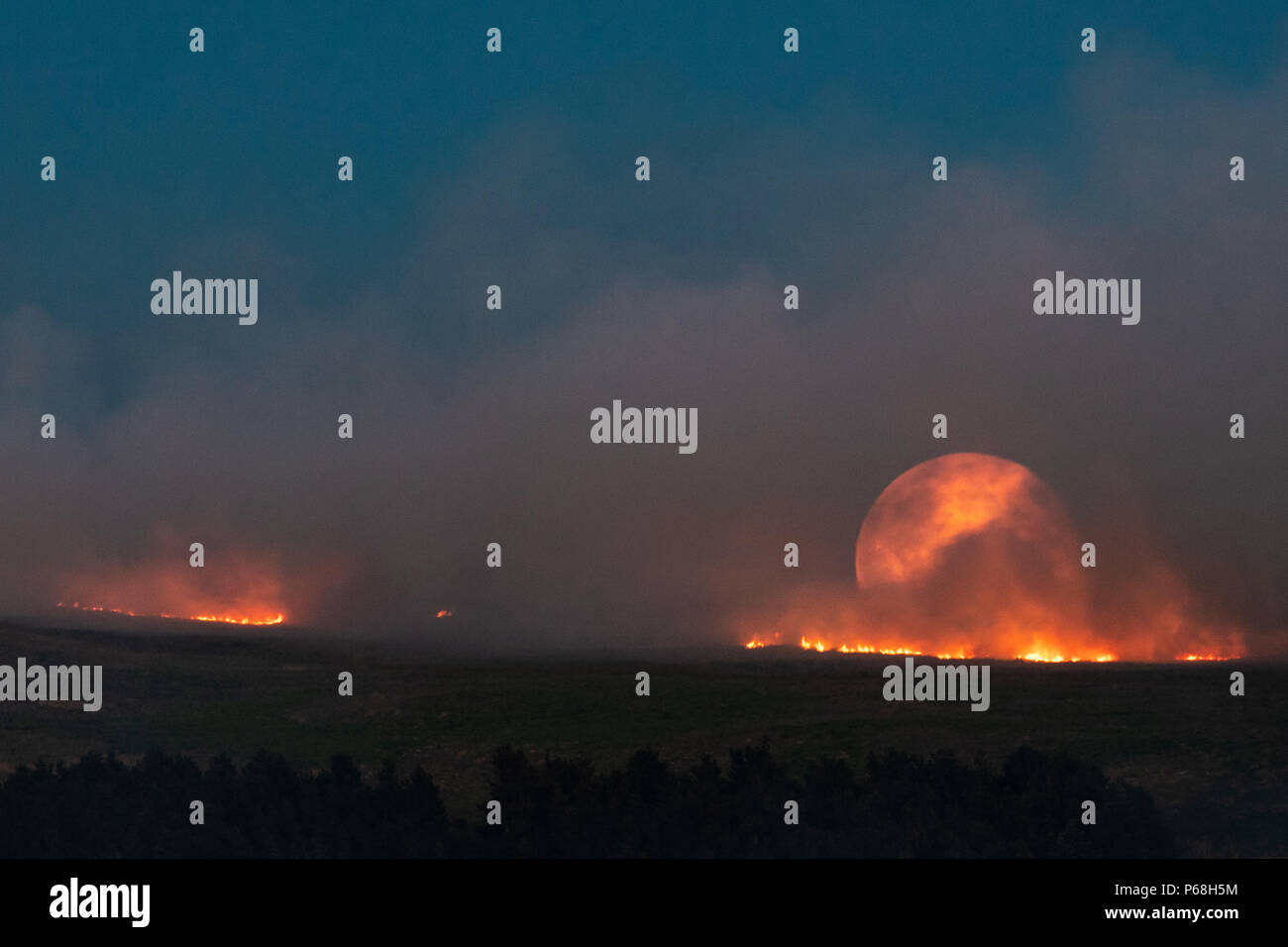 Winter Hill, Greater Manchester, UK. 28th Jun, 2018. The moon rises over a grass fire on the moorlands of Winter Hill, near Bolton in Greater Manchester. Credit: Jason Smalley Photography/Alamy Live News Stock Photo