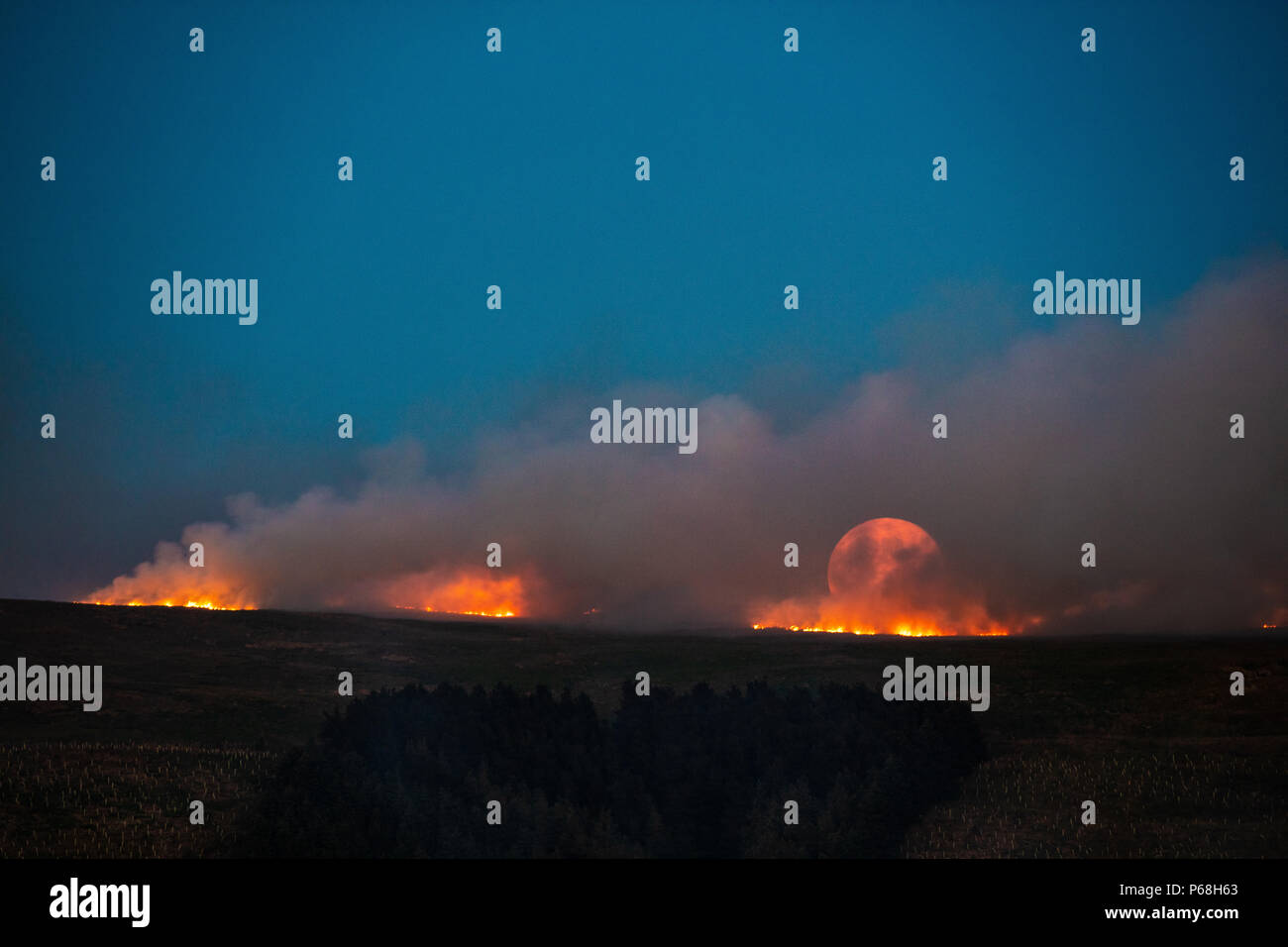 Winter Hill, Greater Manchester, UK. 28th Jun, 2018. The moon rises over a grass fire on the moorlands of Winter Hill, near Bolton in Greater Manchester. Credit: Jason Smalley Photography/Alamy Live News Stock Photo