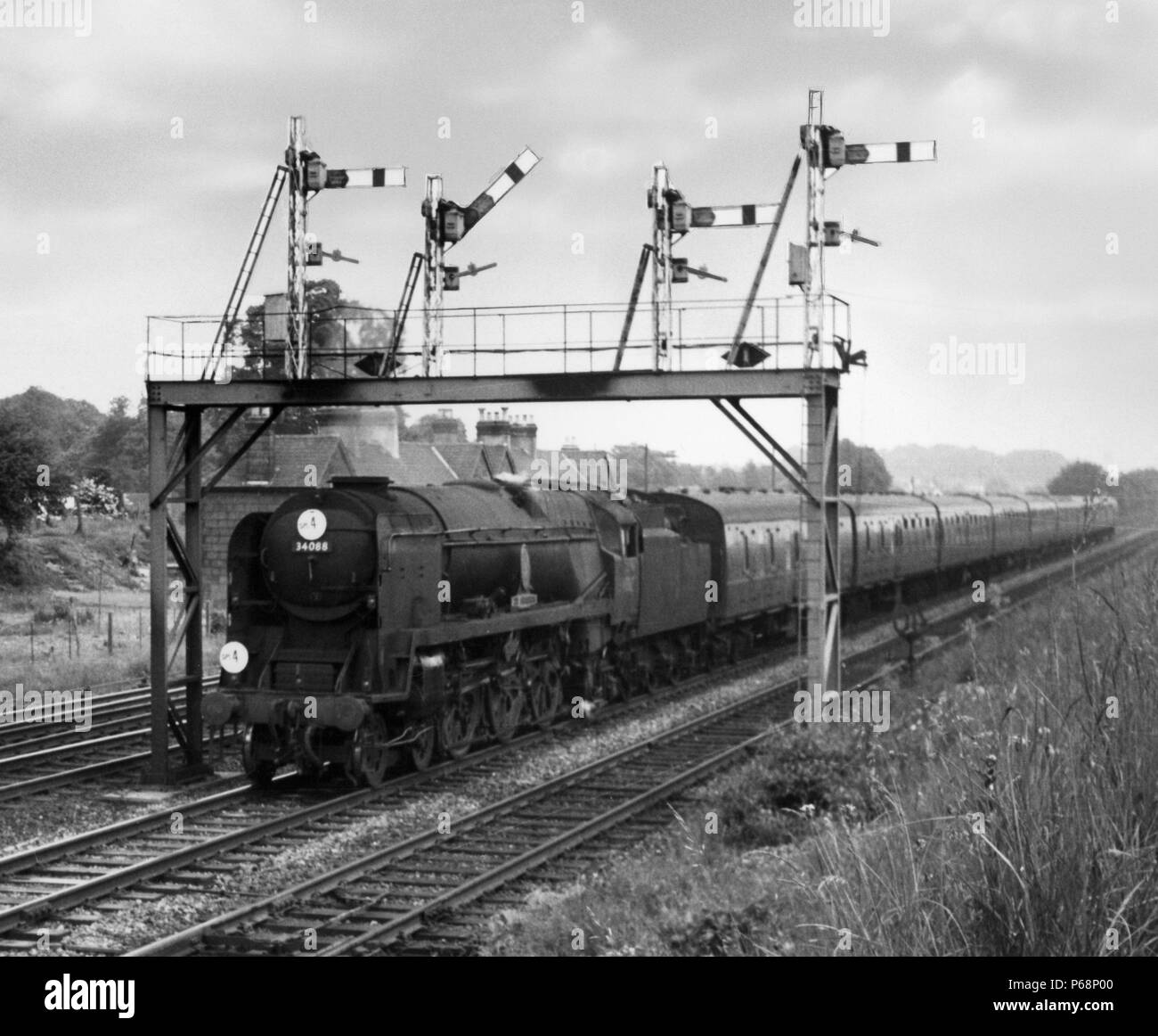 The late great railway enthusiast Brian Stafford watches rebuilt Bulleid Pacific No 34088 '2135 Squadron' pass Worting Junction with a down express in Stock Photo