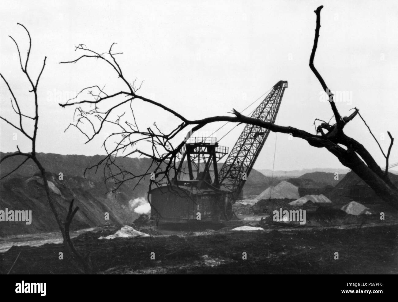 The woodlands retreat as the dragline moves across the workings at Nassington Ironstone Mine in the late 1960s. Poles of Silica white sand - a by-prod Stock Photo