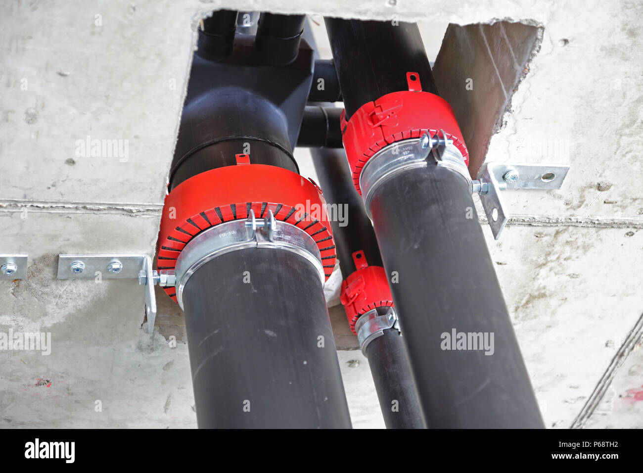 Plastic soil and waste pipes being installed in a new tower block in London, UK. Shows red firetrap collars to maintain integrity of fire compartments Stock Photo