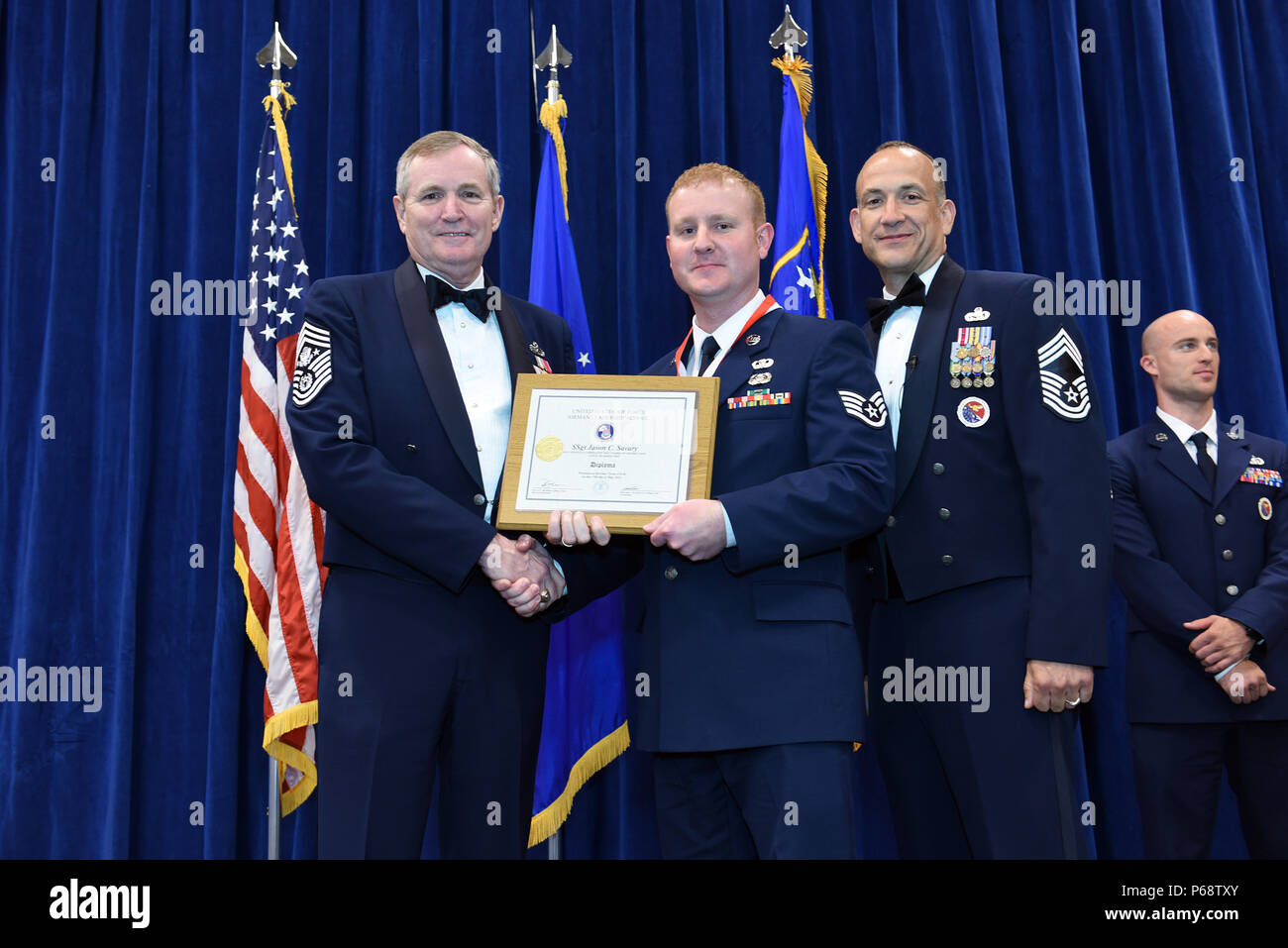 MCGHEE TYSON AIR NATIONAL GUARD BASE, Tenn. – Staff Sgt. Jason Savary, 193rd Special Operations Maintenance Squadron, center, takes his diploma here May 18, 2016, as a distinguished graduate of the Airman leadership school, class 16-5, during the graduation banquet at the Chief Master Sgt. Paul H. Lankford Enlisted Professional Military Education Center. (U.S. Air National Guard photo by Master Sgt. Mike R. Smith/Released) Stock Photo