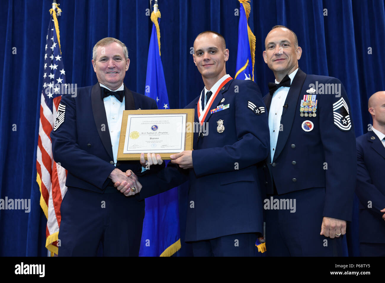 MCGHEE TYSON AIR NATIONAL GUARD BASE, Tenn. – Senior Airman Nathan Droptiny, 110th Security Forces Squadron, center, takes his diploma here May 18, 2016, as a distinguished graduate of the Airman leadership school, class 16-5, during the graduation banquet at the Chief Master Sgt. Paul H. Lankford Enlisted Professional Military Education Center. (U.S. Air National Guard photo by Master Sgt. Mike R. Smith/Released) Stock Photo
