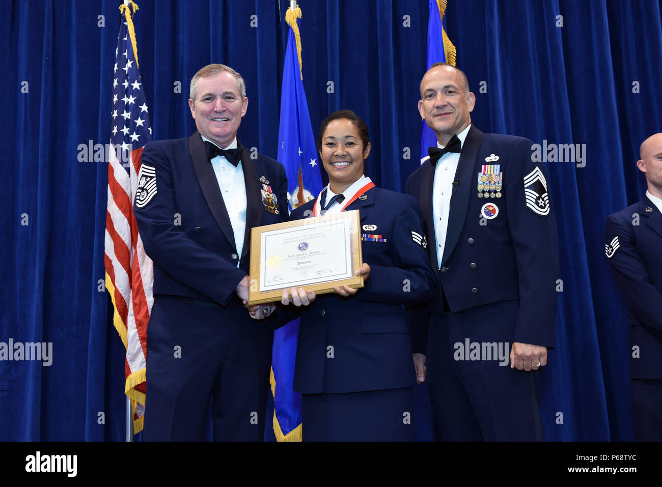 MCGHEE TYSON AIR NATIONAL GUARD BASE, Tenn. – Senior Airman April Dawes, 8th Space Warning Squadron, center, takes her diploma here May 18, 2016, as a distinguished graduate of the Airman leadership school, class 16-5, during the graduation banquet at the Chief Master Sgt. Paul H. Lankford Enlisted Professional Military Education Center. (U.S. Air National Guard photo by Master Sgt. Mike R. Smith/Released) Stock Photo
