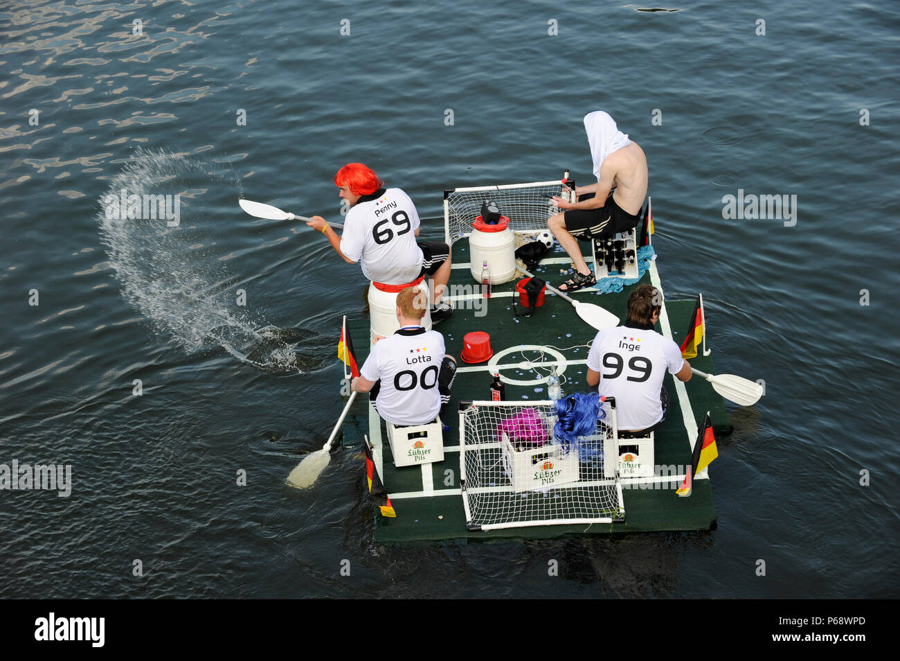 GERMANY, East Germany, Plau, floating mini football field with goal and german flags, four paddling fans in football jersey of German women soccer team and beer box, at funny boat contest and carnival like event Badewannenrallye engl. bathtub rallye, drinking Luebzer beer a brand of Carlsberg Stock Photo