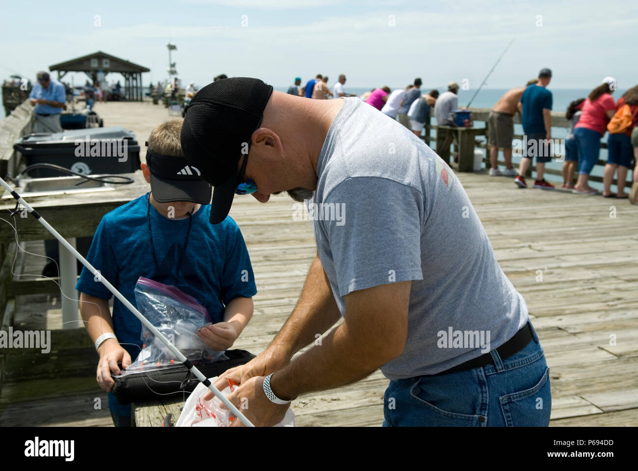 Father and son bait hooks for fishing on pier at Myrtle Beach State