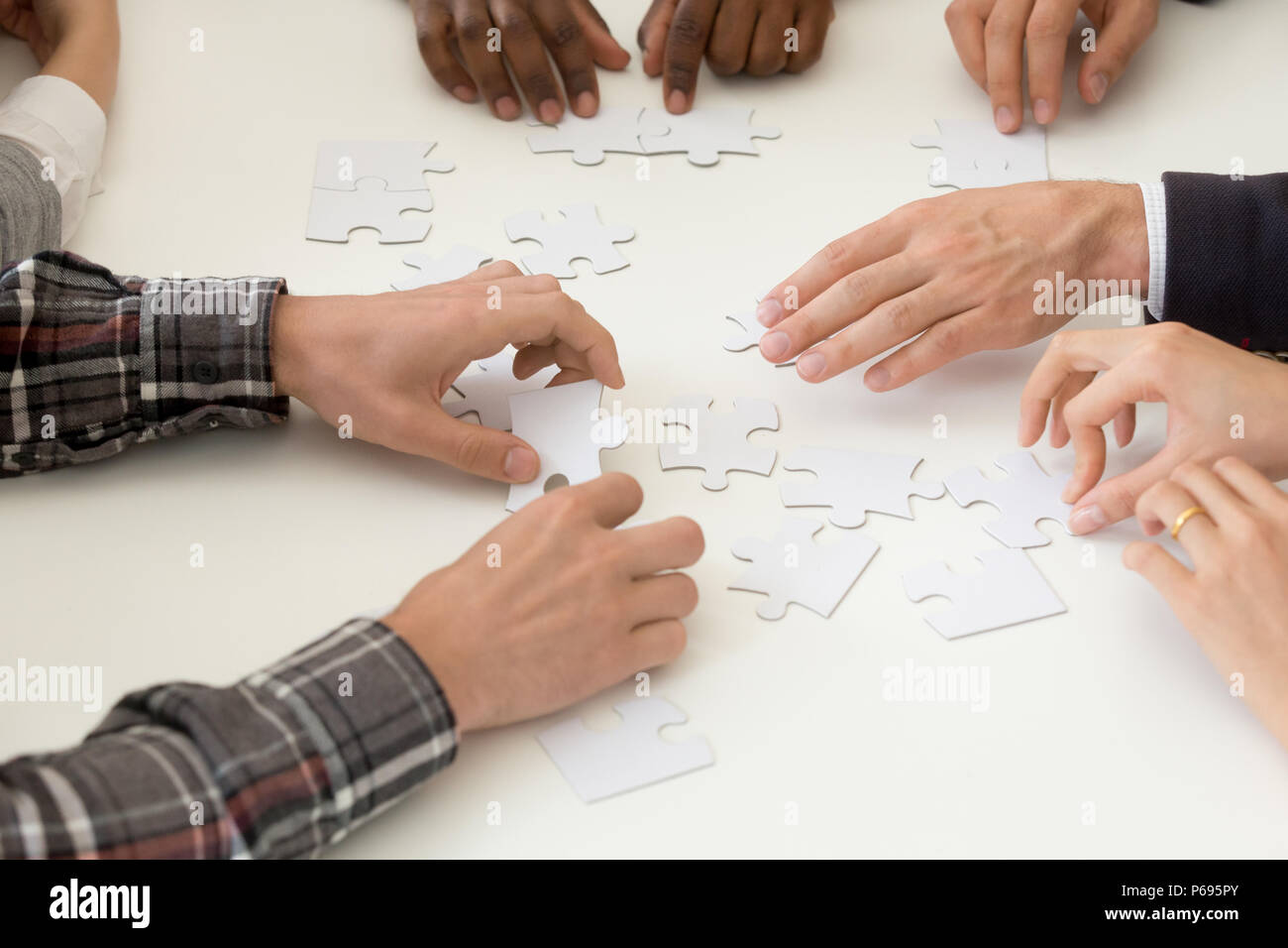 Diverse work team assembling jigsaw at teambuilding activity Stock