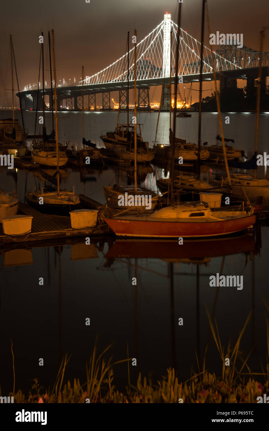 Boats at dock with the Bay Bridge in background at night, San Francisco, North Beach, California, USA Stock Photo