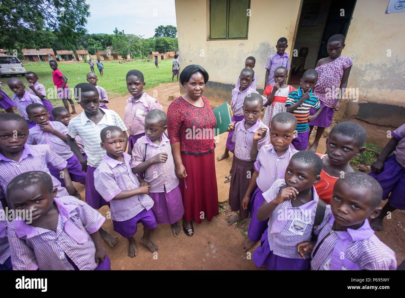 Pupils are seen standing staring with their teacher. Primary school students on their last day of term in a local school near the town of Hoima in western Uganda. Stock Photo