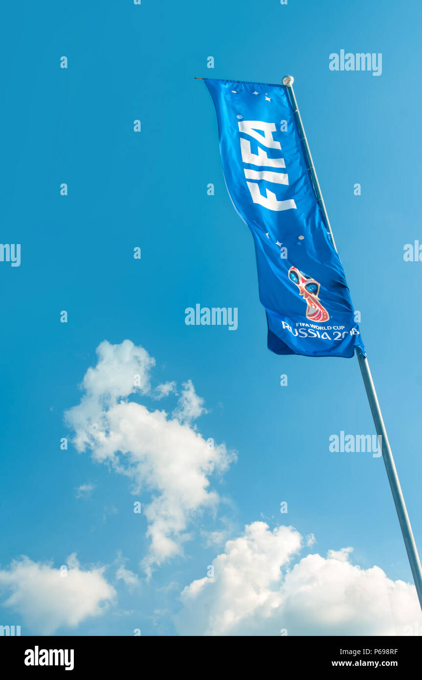 KAZAN, RUSSIA - 25 JUNE, 2018: FIFA world cup flag flying on flag pole against clear blue sky with white clouds near Kazan Arena stadium. Stock Photo
