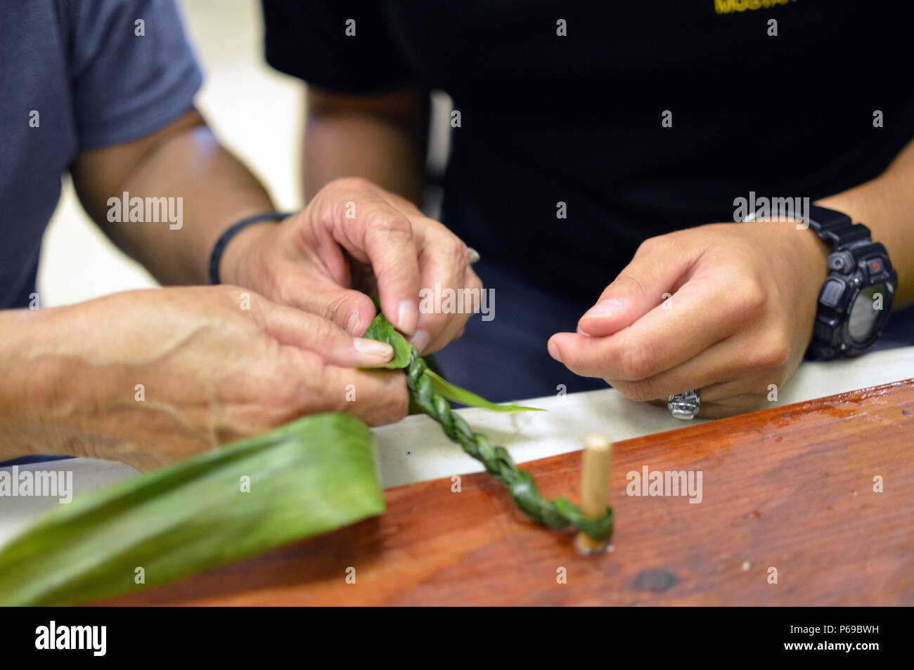 Linda Hirano (left), a Wahiawa Rainbow Seniors volunteer, shows Pfc.  Vanessa Sheika, assigned to the 325th Brigade Support Battalion, 3rd  Brigade Combat Team, 25th Infantry Division, how to make a lei from a ti  leaf at the Wahiawa District Park, Hawaii ...