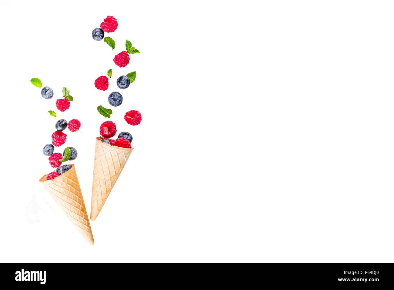 Creative layout with raspberry and blueberry with waffle ice cream cones, simple pattern above copy space Stock Photo