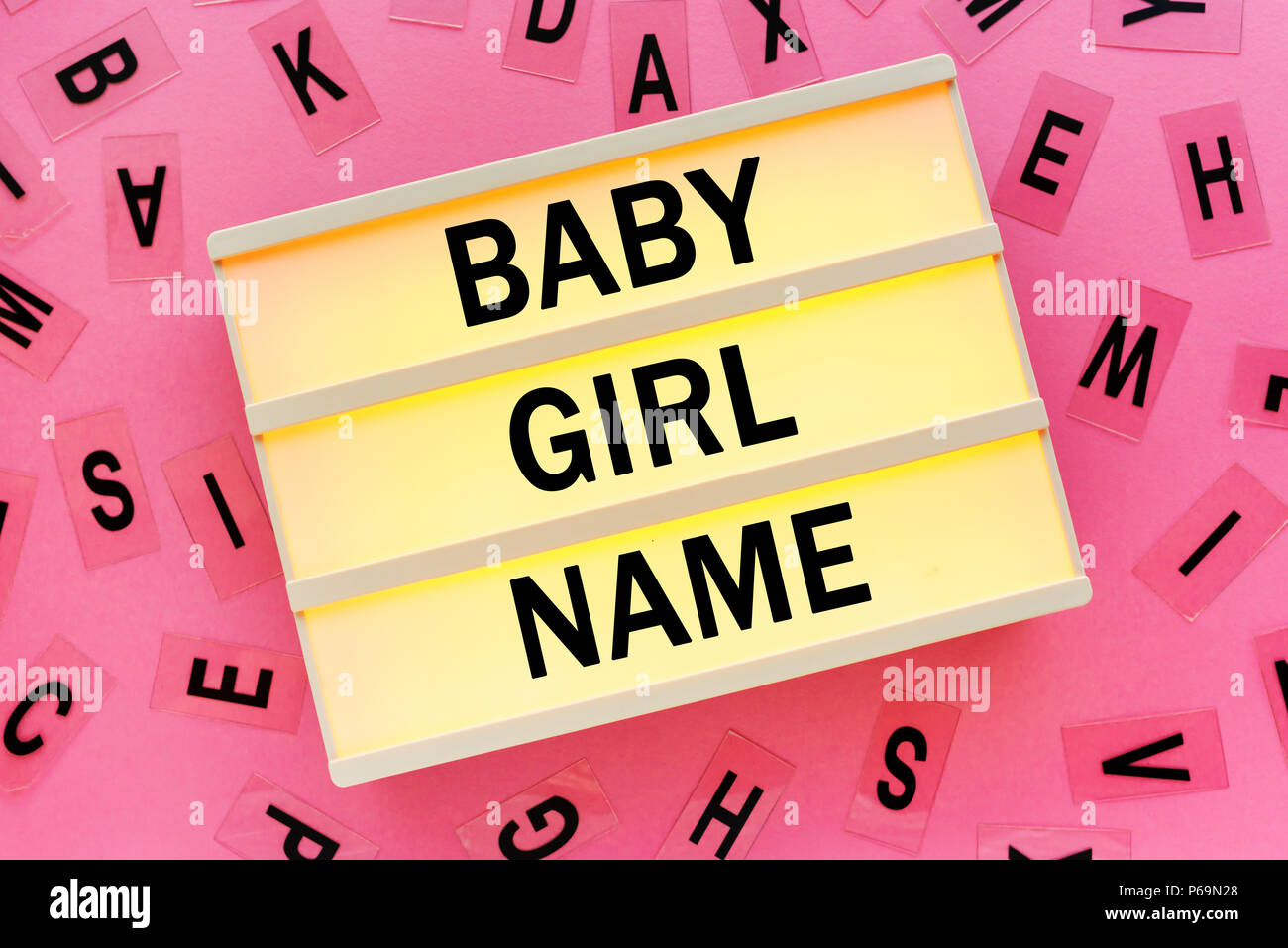Choosing baby girl name concept with lightbox and various letters scattered around Stock Photo
