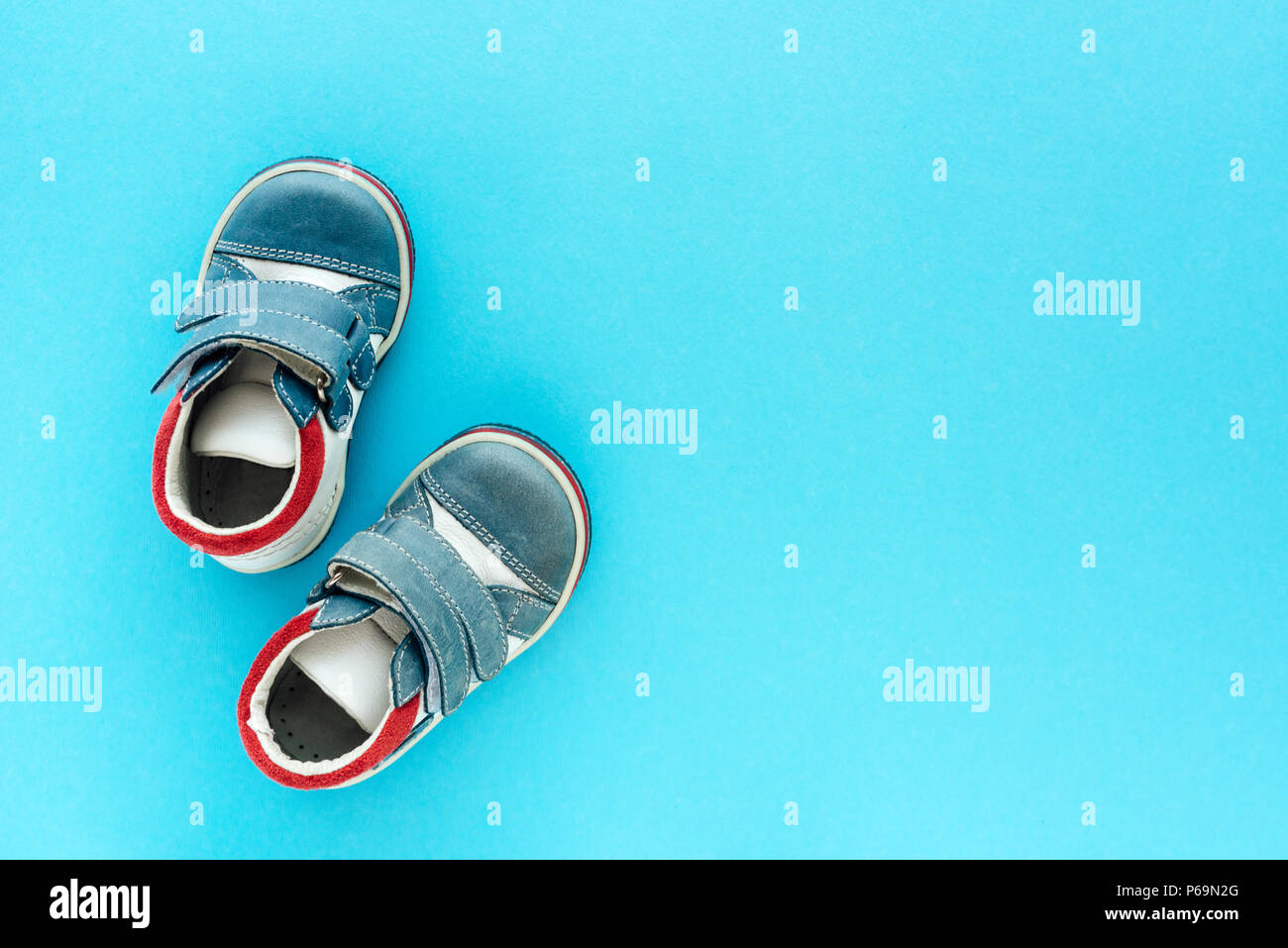 Top view of newborn baby boy shoes on blue background with copy space