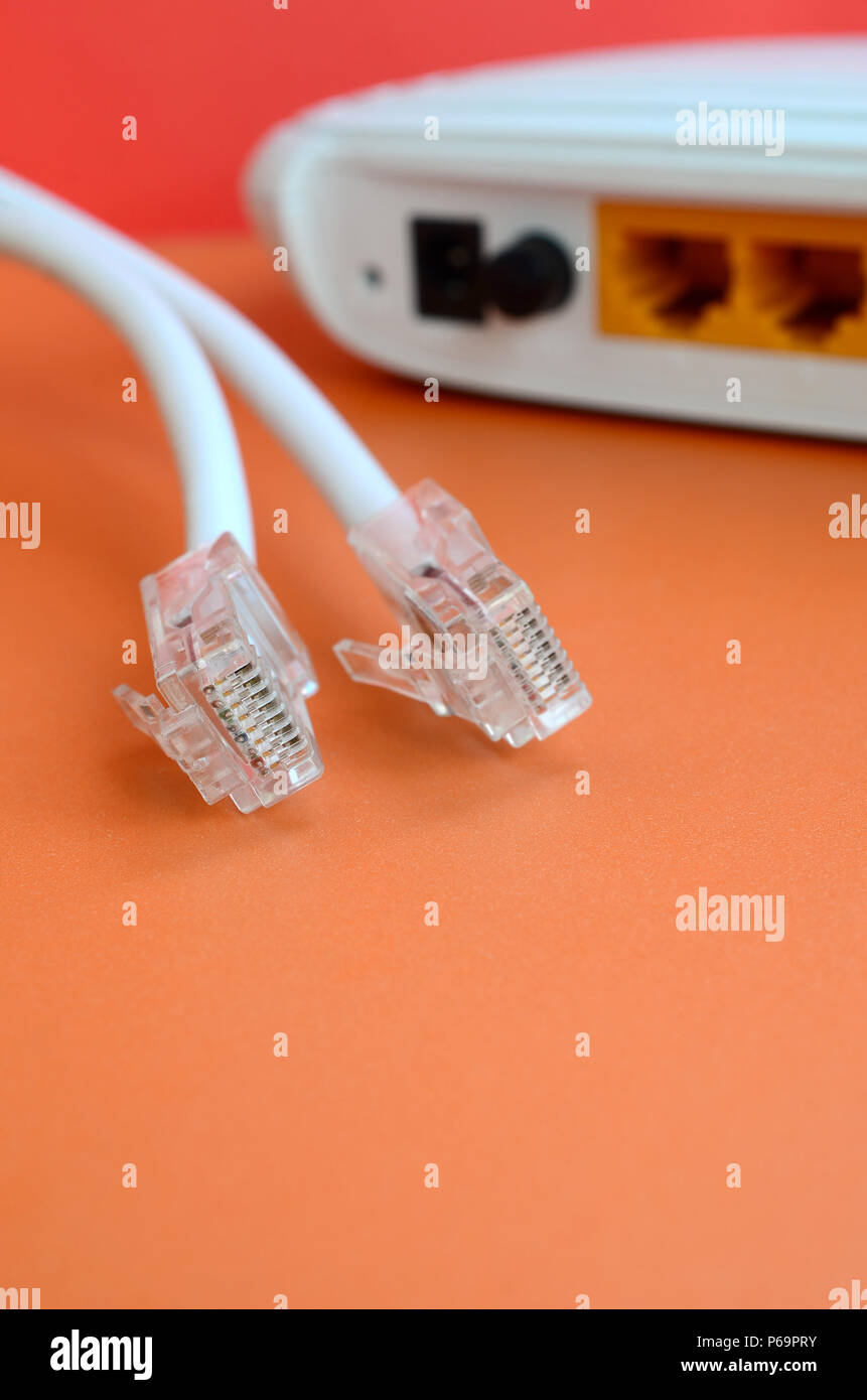 Internet router and Internet cable plugs lie on a bright orange ...