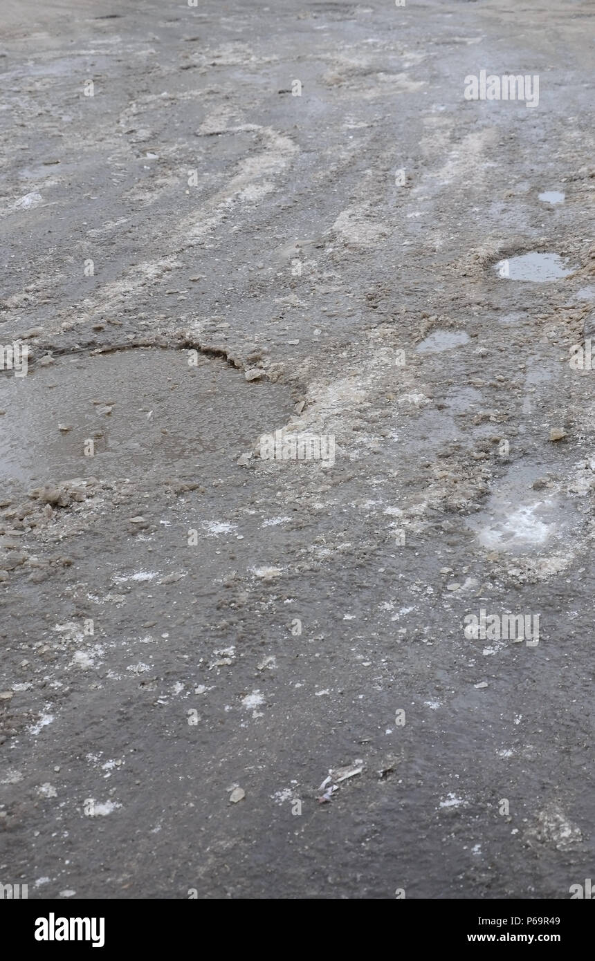 Damaged asphalt road with potholes caused by freezing and thawing ...