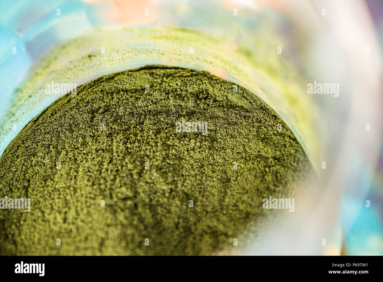 Overhead closeup view of jar with fresh green spirulina powder on kitchen table. Stock Photo