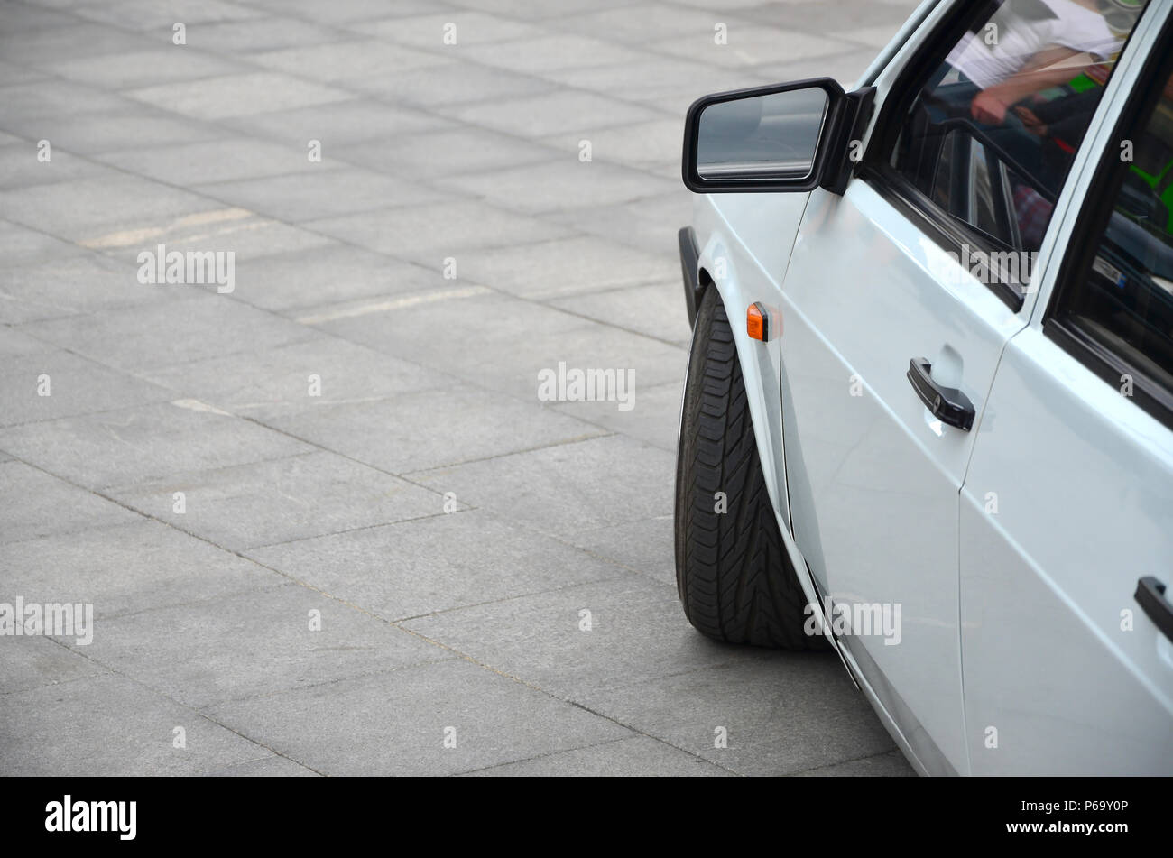 Diagonal view of a white glossy car that stands on a square of gray ...
