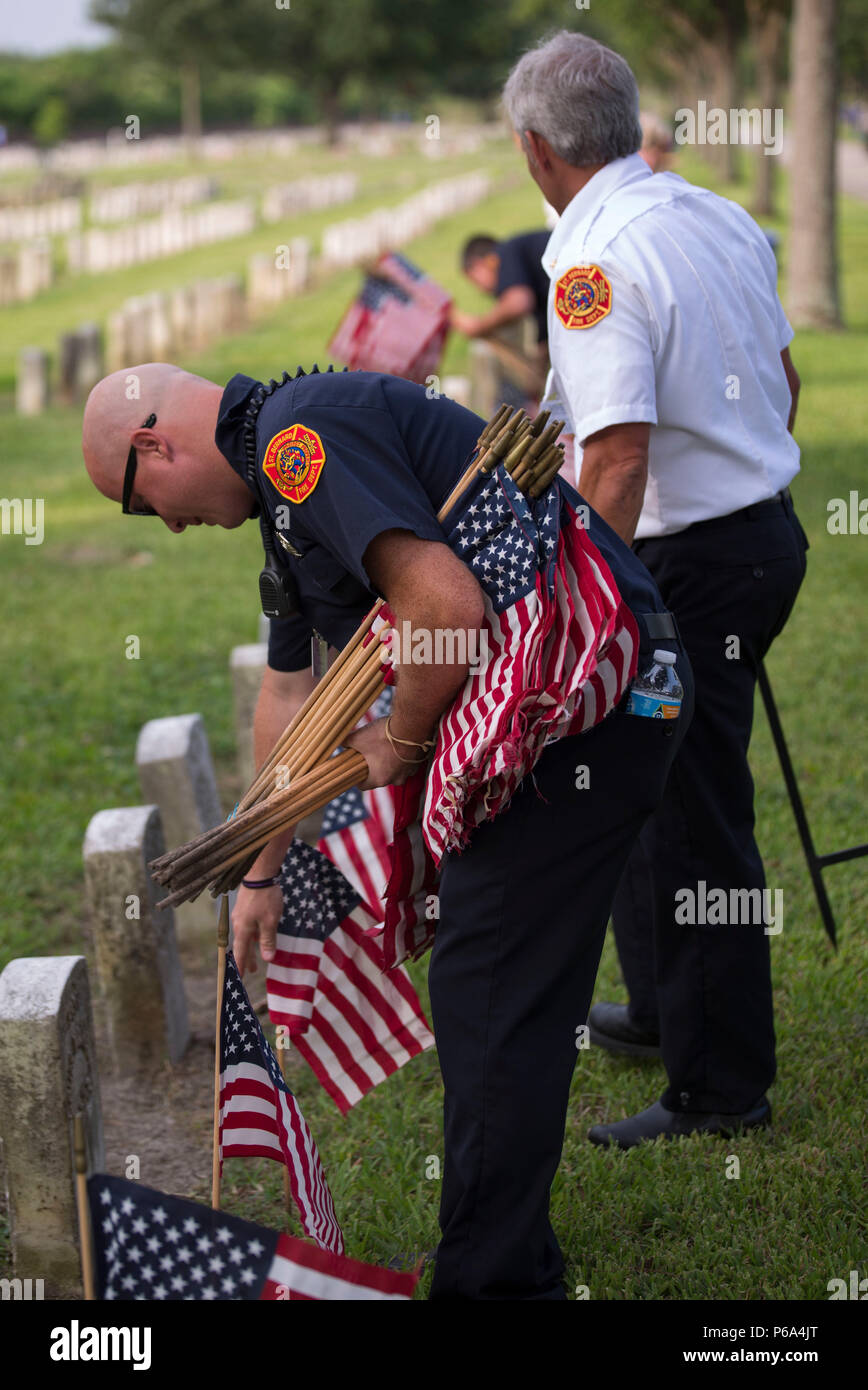 Howard Beal, a firefighter with the St. Bernard Fire Department, places a flag at the tombstone of a fallen service member during a Memorial Day volunteer event at Chalmette National Cemetery in Chalmette, La., May 27, 2016. Hundreds of volunteers placed flags at the service members’ final resting place as part of the annual event of paying respects to the fallen service members. (U.S. Marine Corps photo by Lance Cpl. Devan A. Barnett) Stock Photo
