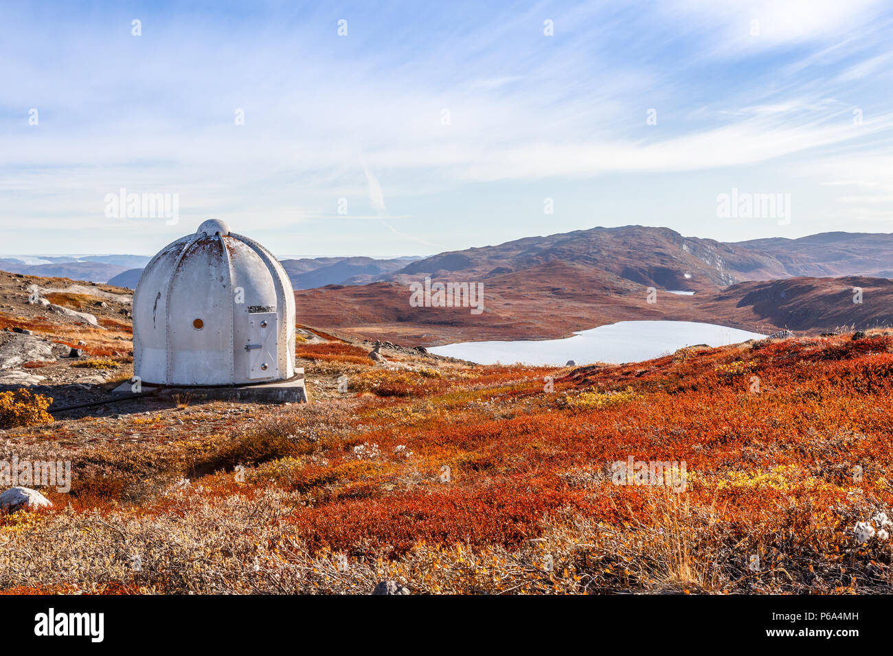 Metal US bunker and autumn greenlandic orange tundra landscape with lakes and mountains in the background, Kangerlussuaq, Greenland Stock Photo