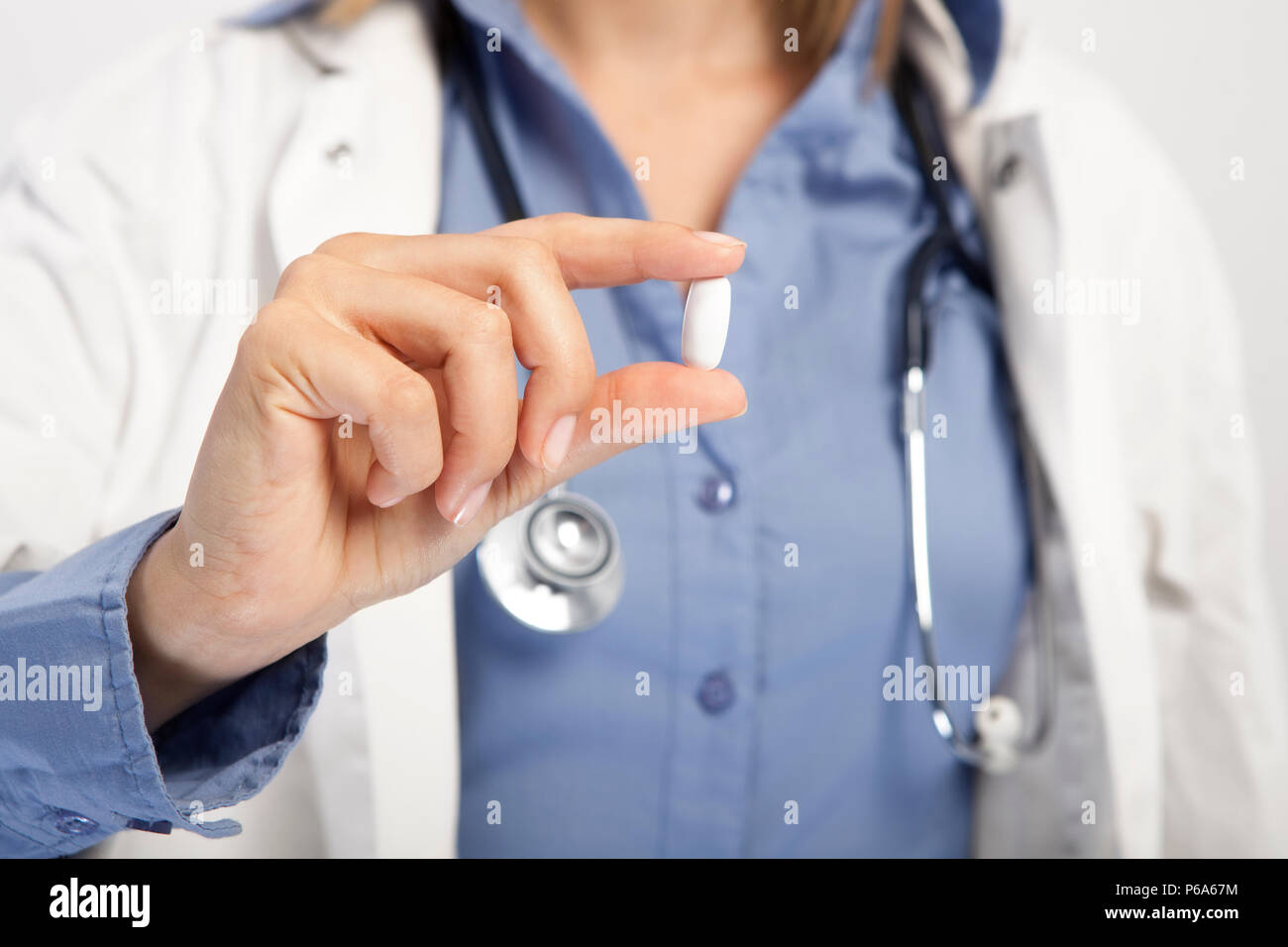 a doctor holds a white pill in the camera, no face Stock Photo