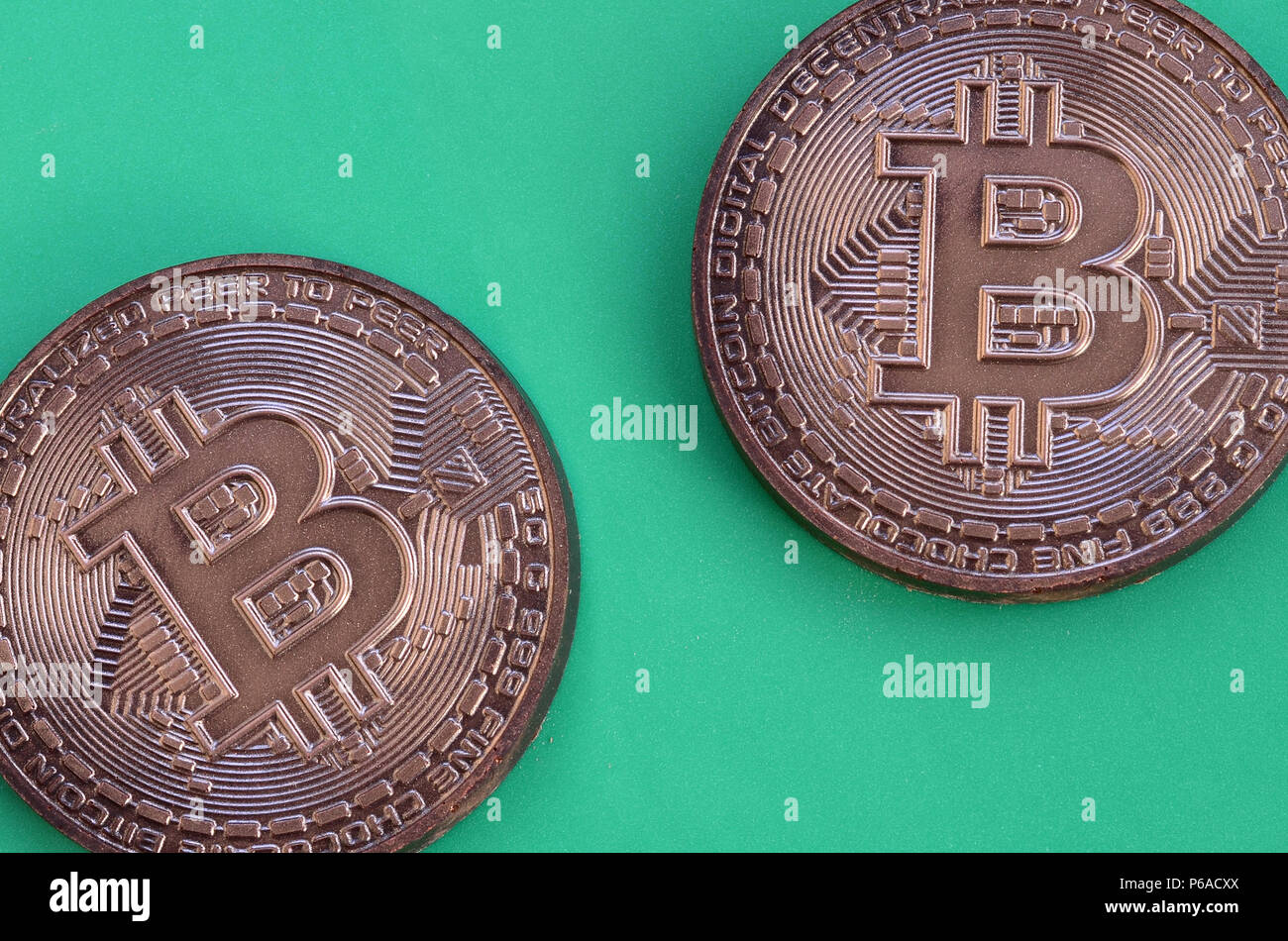 Two chocolate products in the form of physical bitcoins lie on a green  plastic background. Model of the crypto currency in the edible form Stock  Photo - Alamy