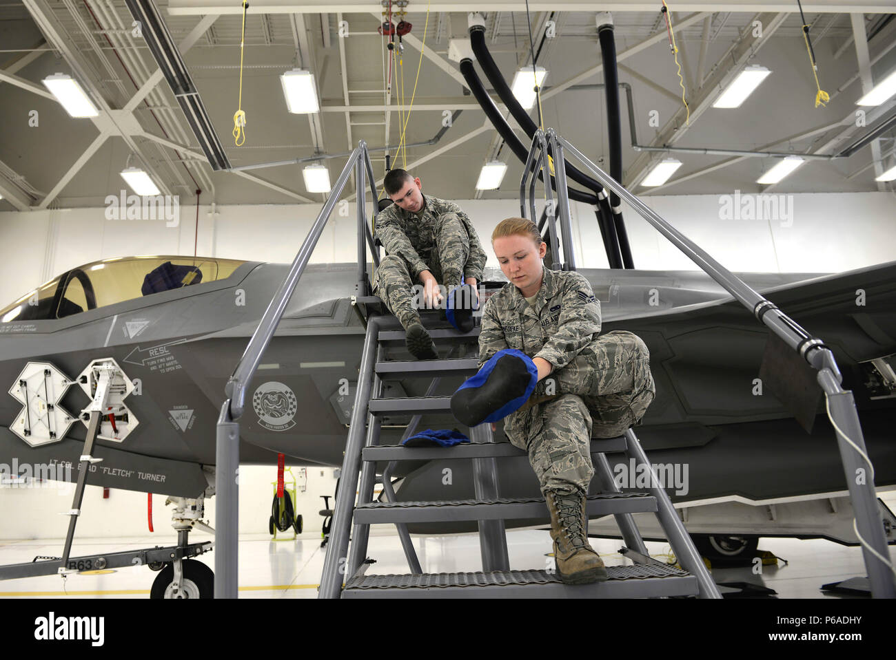 (Right) Senior Airman Samantha Schmedeke, 33rd Maintenance Squadron fuel systems journeyman, and (Left) Airman 1st Class William Manion, 33rd MXS fuel systems apprentice, put on booties before walking atop an F-35A Lightning II to perform maintenance at Eglin Air Force Base, Fla., May 16, 2016. Fuel systems specialists wear these protective coverings to avoid scuffing the low observable paint, which is part of the stealth effect on the jet. (U.S. Air Force photo/Senior Airman Andrea Posey) Stock Photo