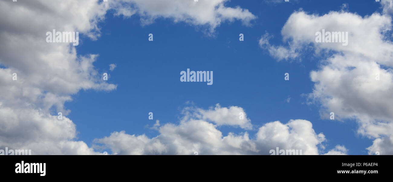 The blue sky with a lot of white clouds of different sizes, forming a frame around the cloudless area . Stock Photo