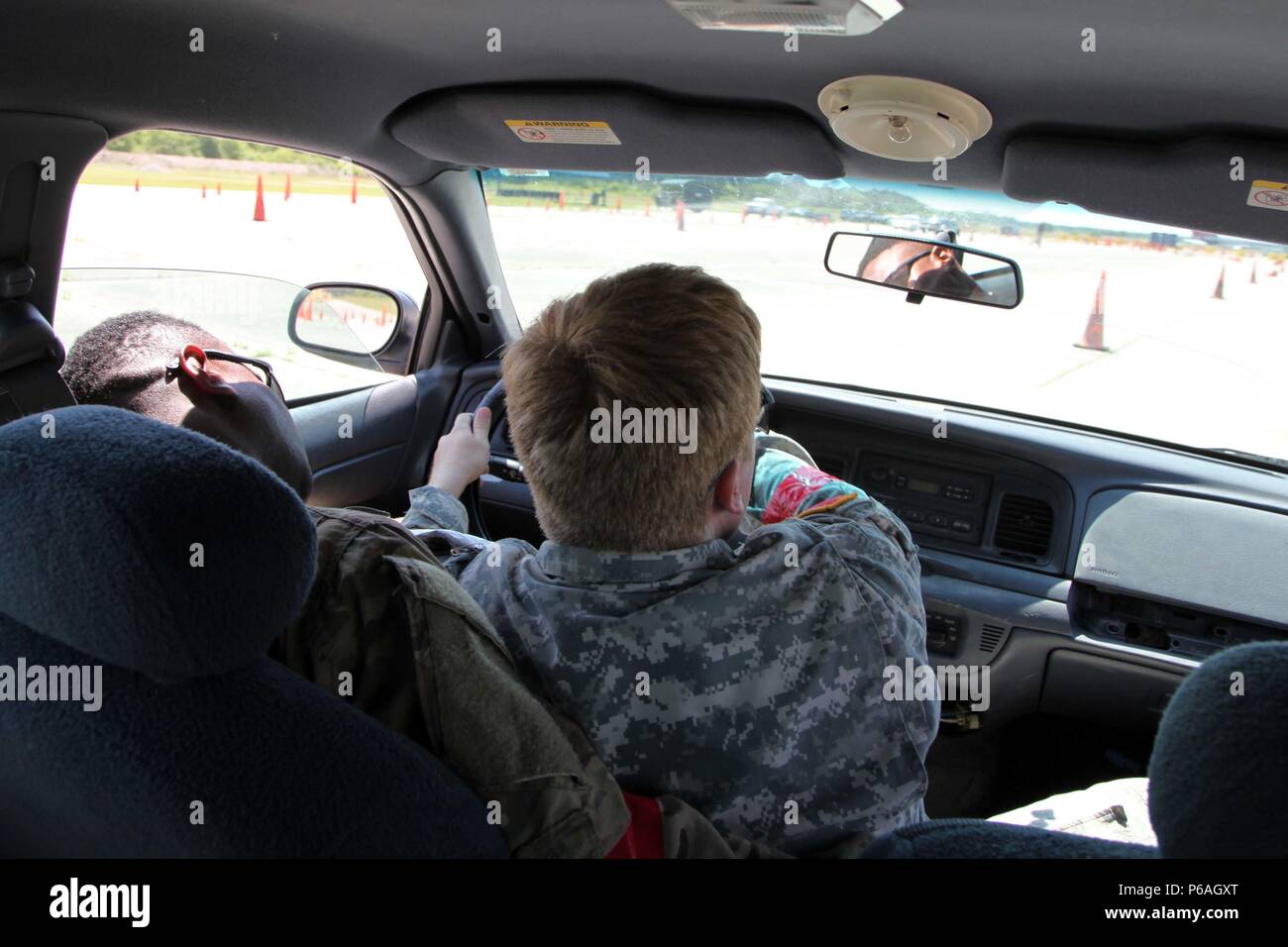 A U.S. Soldier assigned to 4th Military Information Support Group practices taking over the steering wheel from an “incapacitated” driver on Gryphon Group Security Solutions’ evasive driving course, May 4, 2016. Soldiers practiced driving a vehicle from the passenger seat in the event that the driver was injured. They also learned to maneuver through tight environments at high speeds, as well as first aid techniques and advanced pistol marksmanship during the week-long course at the Fort Bragg Combat Training Center in Maxton, North Carolina. Stock Photo