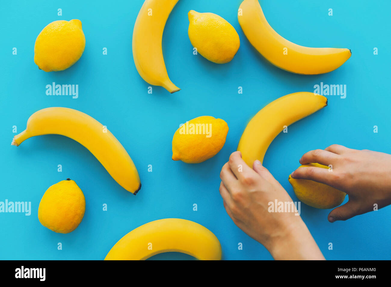 yellow bananas and lemons on blue trendy paper background, flat lay