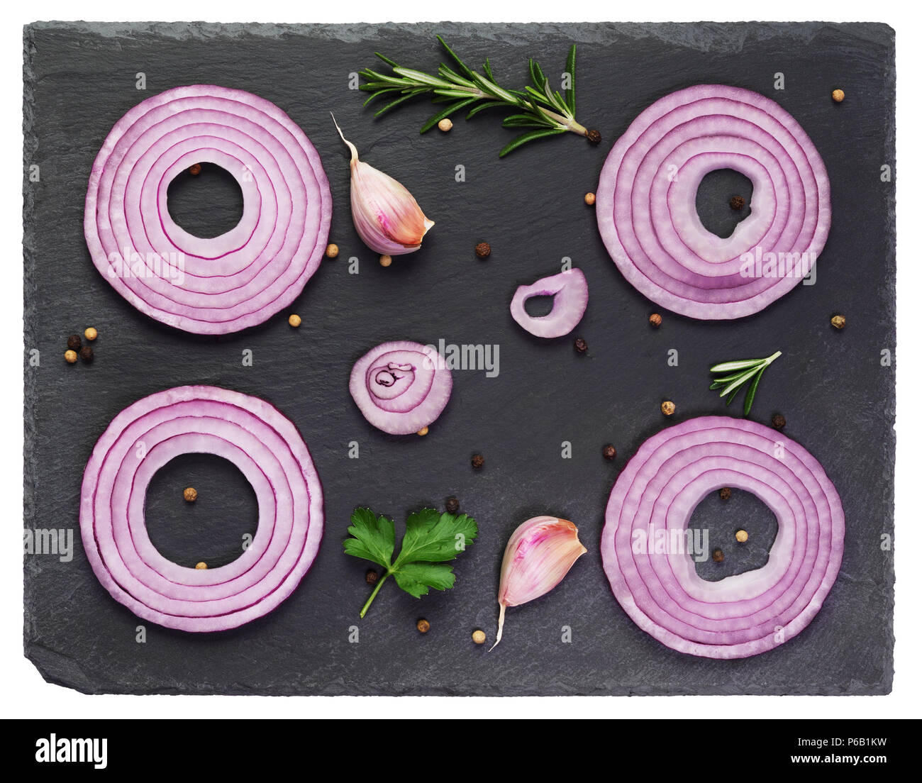 Sliced red onions set with spices and herbs on black stone background.Top view Stock Photo