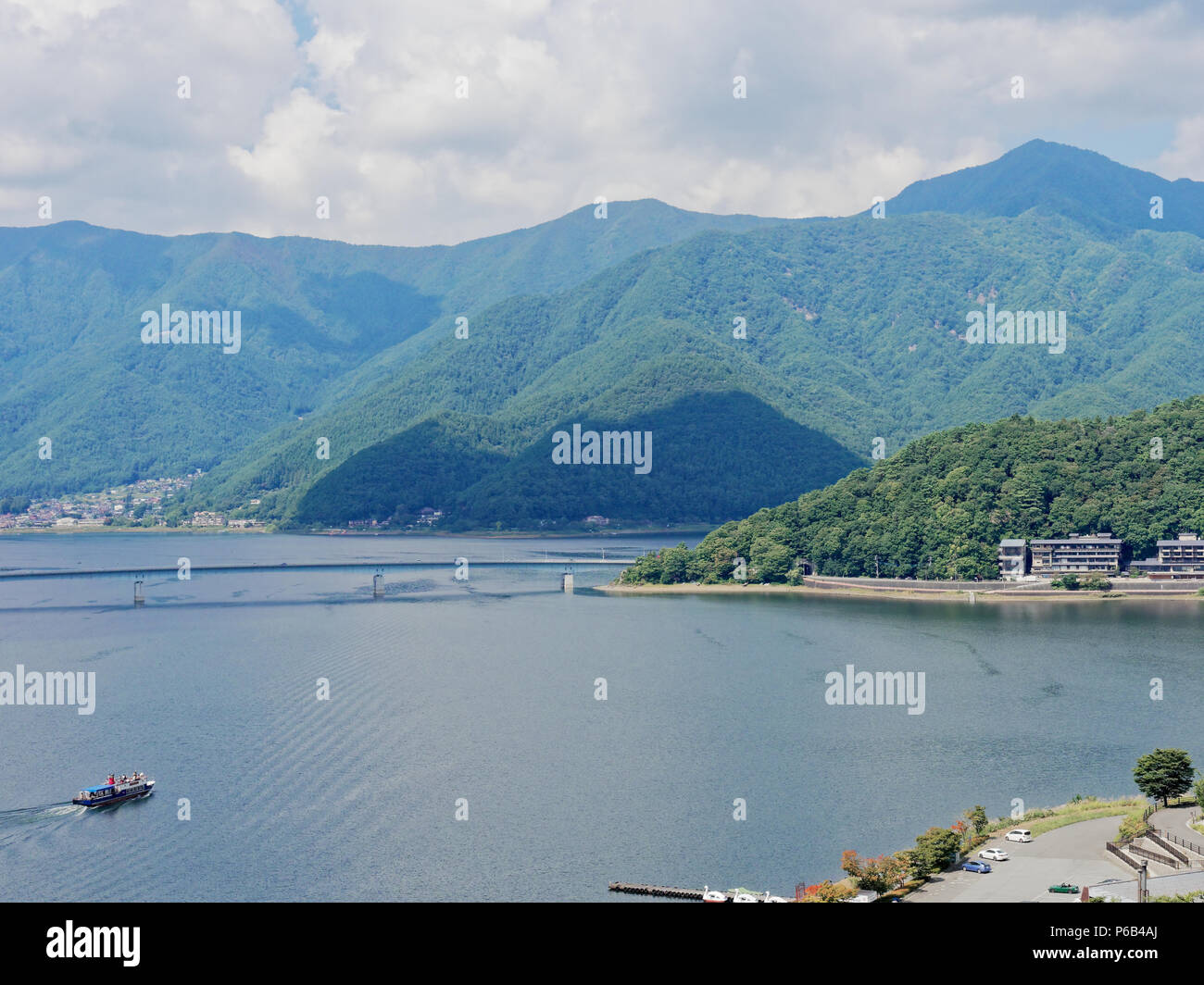 Scenery of Lake Kawaguchi, the biggest lake of Fuji five lakes, with a ferry boat and an overwater bridge crossing the lake and mt Kurodake on the background, famous tourist destination in Japan Stock Photo