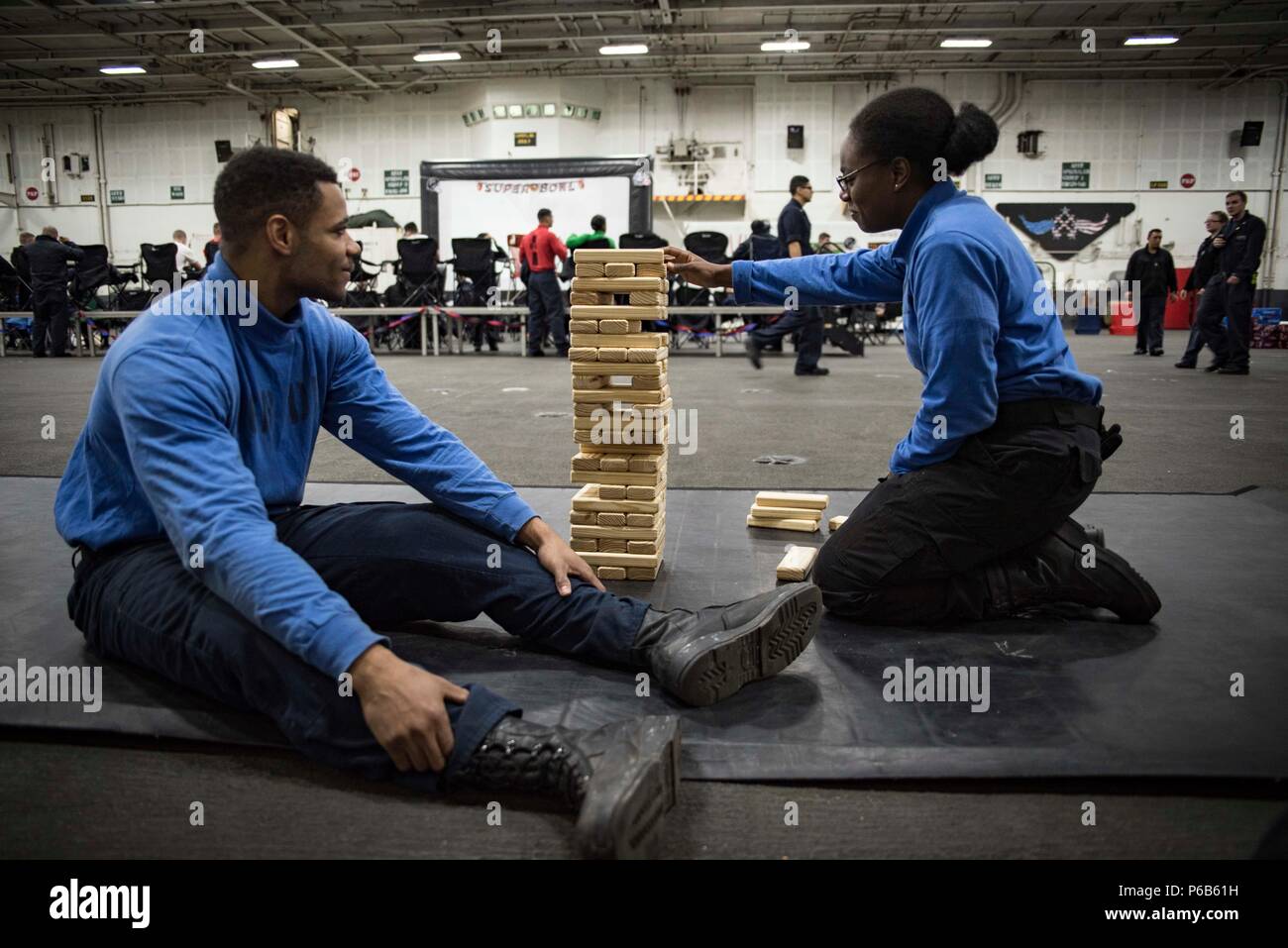 170205-N-IE397-016 ATLANTIC OCEAN (Feb. 5, 2017) Airman Michael Hudtins, left, and Aviation Boatswain's Mate (Handling) Airman Shanterica Green, play Jenga in the hangar bay of the aircraft carrier USS Dwight D. Eisenhower (CVN 69) during Super Bowl festivities provided by the ship's Morale, Welfare and Recreation department. Dwight D. Eisenhower is conducting aircraft carrier qualifications during the sustainment phase of the Optimized Fleet Response Plan. (U.S. Navy photo by Mass Communication Specialist 3rd Class Christopher A. Michaels/Released) Stock Photo