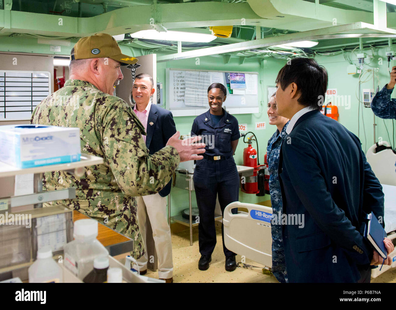 180621-N-SD711-0075 SASEBO, Japan (June 21, 2018) Capt. Michael Harris, executive officer of the San Antonio-class amphibious transport dock ship USS Green Bay (LPD 20), gives a tour of the medical bay to Takahiro Suzuki, Ministry of Foreign Affairs Status of Forces Agreement deputy director, North American Affairs Bureau, aboard Green Bay, June 21, 2018. The tour of CFAS and the ship was given to increase his understanding of CFAS’ capabilities in support of the U.S.-Japan alliance. (U.S. Navy photo by Mass Communication Specialist 3rd Class Geoffrey P. Barham/Released) Stock Photo
