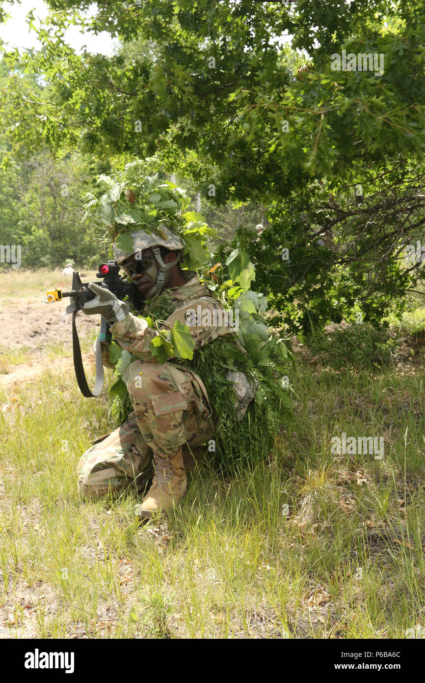Pfc. Prince Assie, a plumber with the 1194th Engineer Company out of Chillicothe, Ohio, pulls security during a platoon defense exercise on June 22 at Camp Grayling Joint Maneuver Training Center in Grayling, Mich. The goal of the mission is to improve soldiers' tactical skills and communication. (Ohio Army National Guard photo by Spc. Emilie Sheridan/Released) Stock Photo