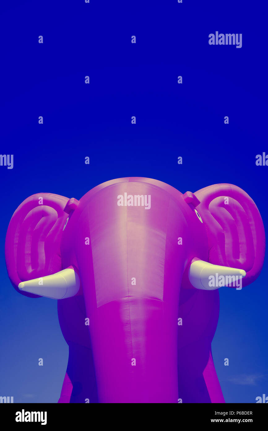 Pink big inflatable elephant with white tusks on a blue sky background Stock Photo