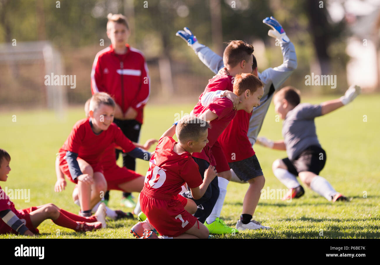 Kids soccer football - young children players celebrating in hug after victory Stock Photo