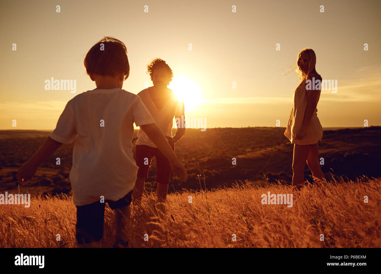 Happy family having fun playing at sunset on nature. Stock Photo