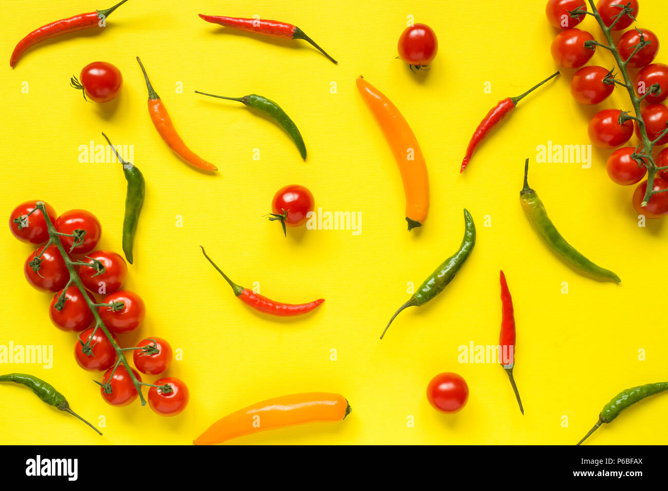 Assorted chili pepper tomato cherry On yellow bright background. Stock Photo