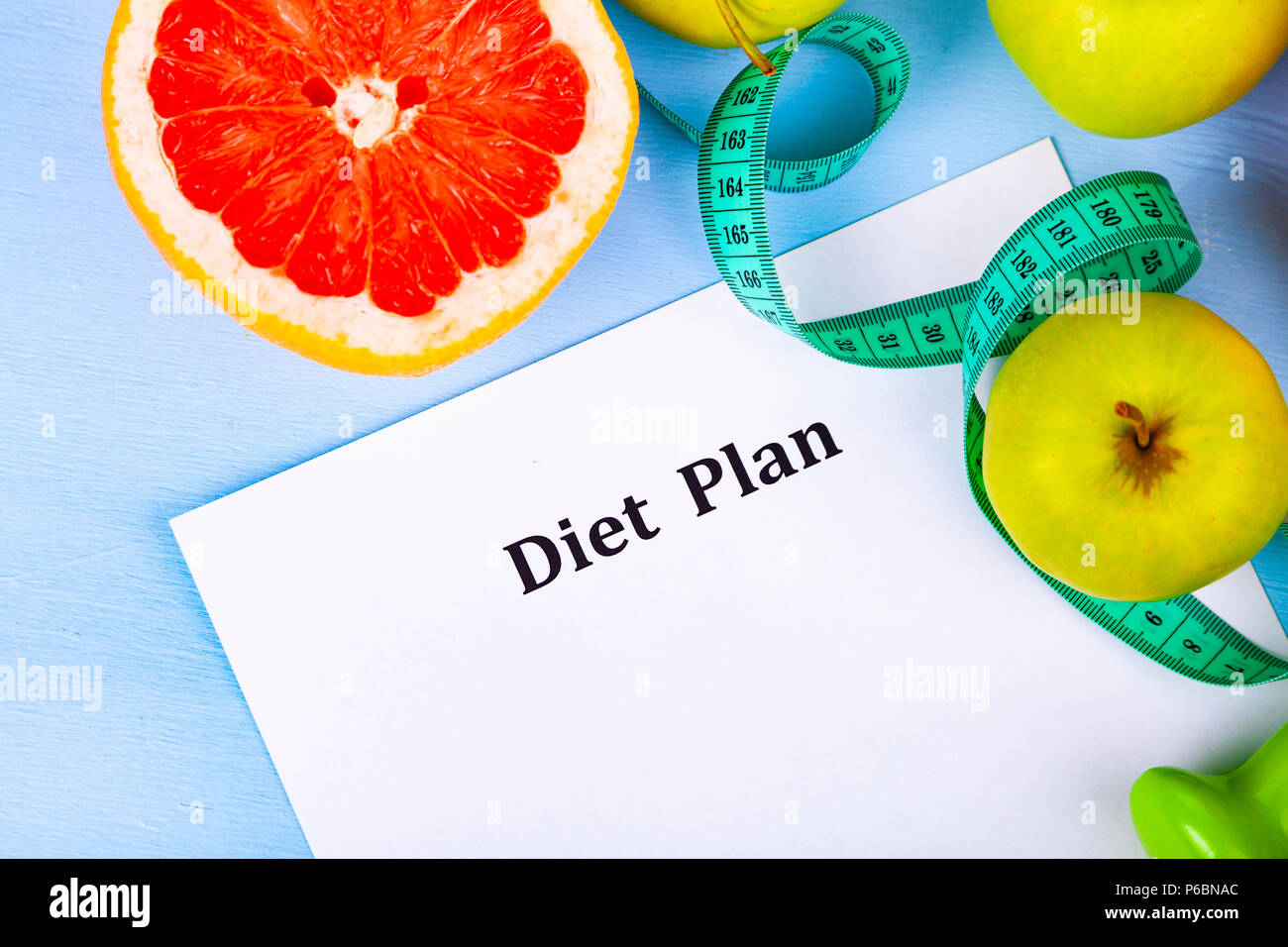 Food and sheet of paper with a diet plan on a blue wooden background ...