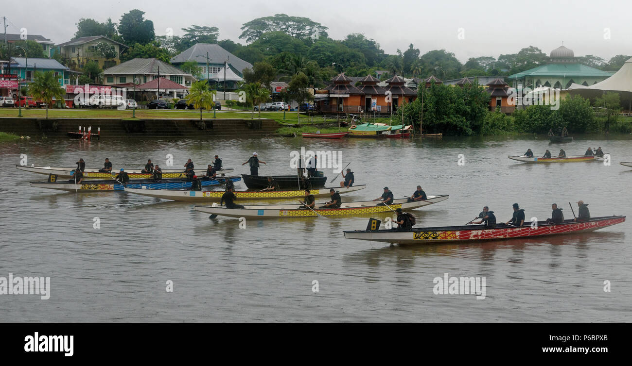 Malaysian services and forces practice for the Gawai procession on the Sarawak river, Kuching, Borneo with a malay kampong behind Stock Photo