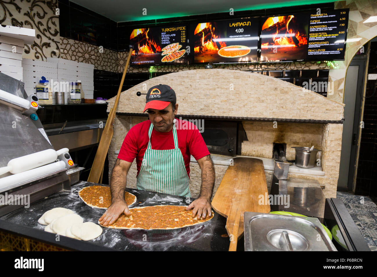 Pizza chef preparing pizzas in front of the pizzeria oven at Moo's