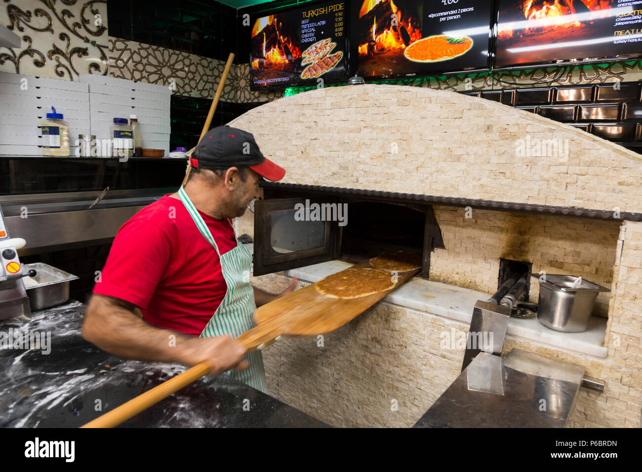Pizza chef preparing pizzas in front of the pizzeria oven at Moo's