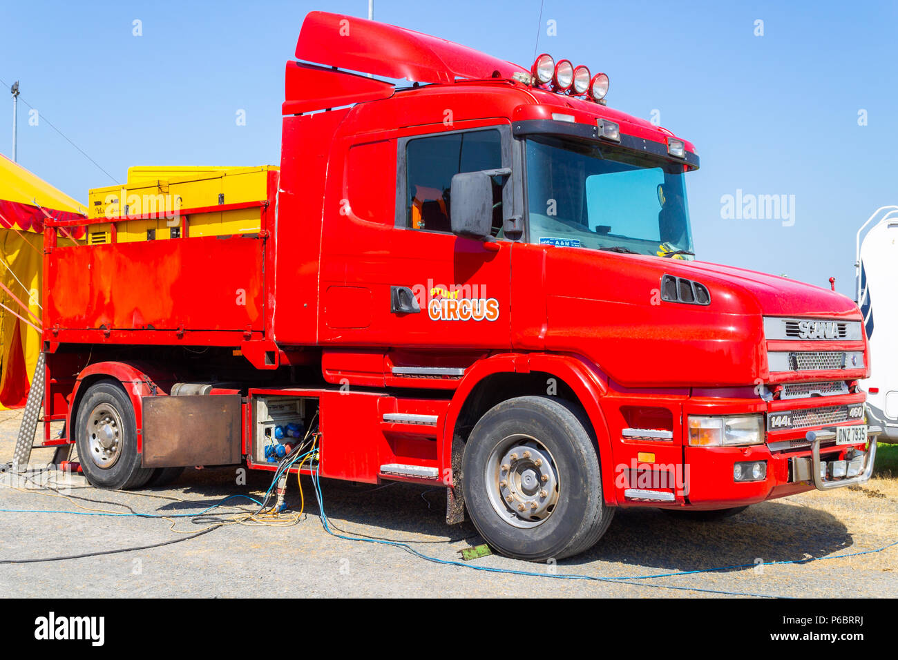Scania lorry or truck painted bright red in circus colours supplying power to the circus. circus lorry or circus truck Stock Photo